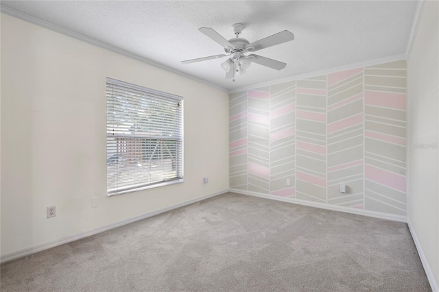 empty room with a textured ceiling, ceiling fan, carpet, and crown molding