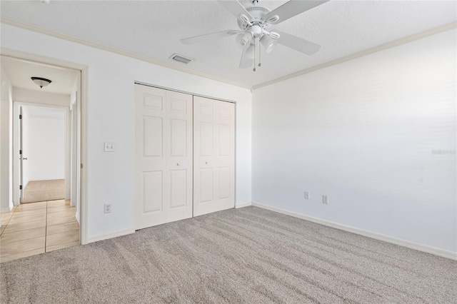 unfurnished bedroom featuring carpet floors, ornamental molding, a closet, and visible vents