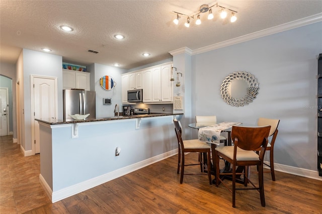 kitchen featuring arched walkways, a sink, white cabinetry, a kitchen breakfast bar, and appliances with stainless steel finishes