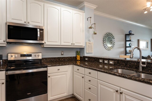 kitchen with dark stone counters, appliances with stainless steel finishes, a sink, and crown molding