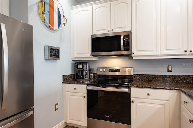 kitchen featuring dark stone counters, stainless steel appliances, and white cabinets