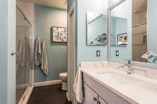 bathroom with a stall shower, wood finish floors, vanity, and toilet