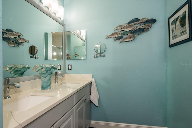 bathroom with double vanity, baseboards, and a sink