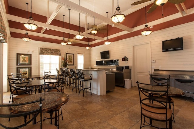 kitchen with a breakfast bar, decorative light fixtures, ceiling fan, and wooden walls