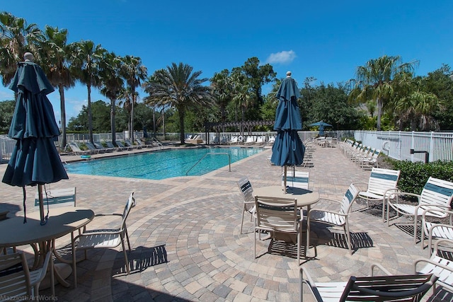 community pool with a patio area and fence