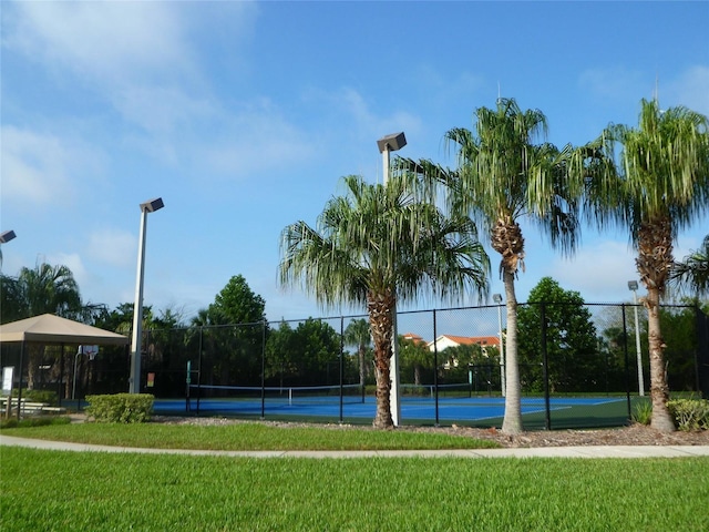 view of home's community with a tennis court, a yard, and fence