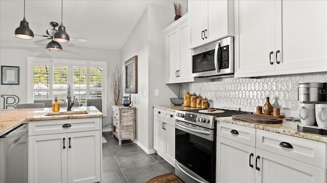 kitchen featuring pendant lighting, tasteful backsplash, appliances with stainless steel finishes, white cabinets, and a sink