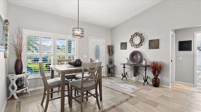 dining area with light wood-style floors, lofted ceiling, and baseboards