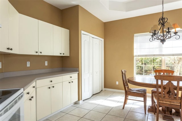 kitchen featuring light tile patterned floors, white electric stove, a chandelier, decorative light fixtures, and white cabinetry