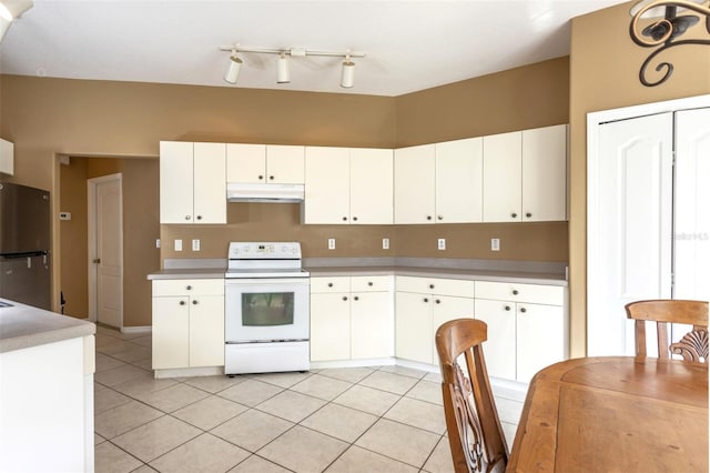 kitchen featuring freestanding refrigerator, electric stove, under cabinet range hood, and light tile patterned floors