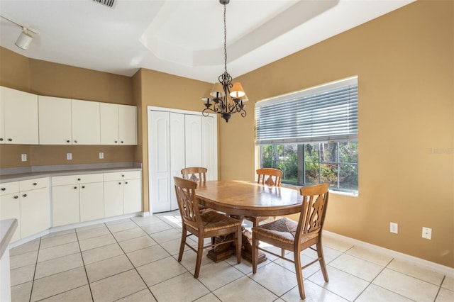 dining area featuring a chandelier, a tray ceiling, baseboards, and light tile patterned floors