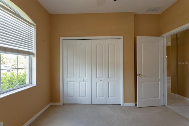 unfurnished bedroom featuring baseboards, visible vents, a closet, and light colored carpet