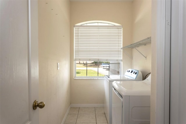 laundry area featuring laundry area, baseboards, washer and clothes dryer, and light tile patterned flooring