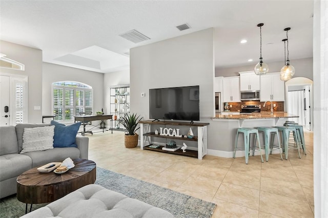 living room featuring recessed lighting, visible vents, arched walkways, and light tile patterned flooring