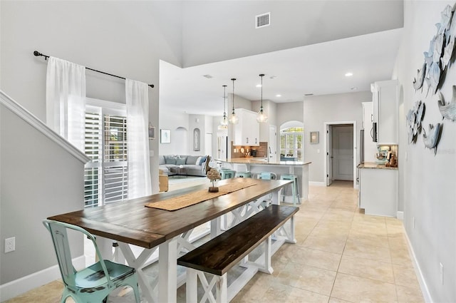 dining room featuring light tile patterned floors, arched walkways, visible vents, and baseboards