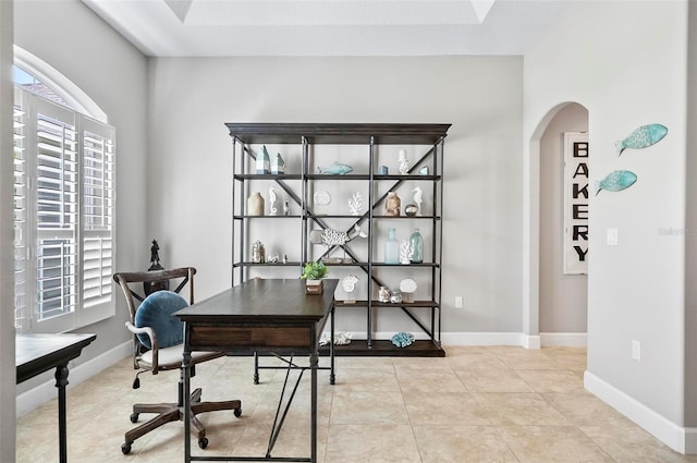 tiled office space featuring arched walkways and baseboards