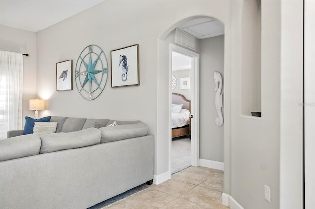 living area featuring arched walkways, light tile patterned floors, and baseboards