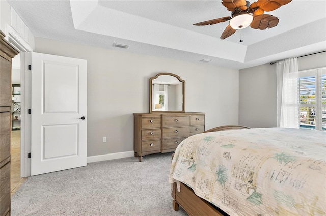 bedroom with light carpet, a ceiling fan, a tray ceiling, a textured ceiling, and baseboards