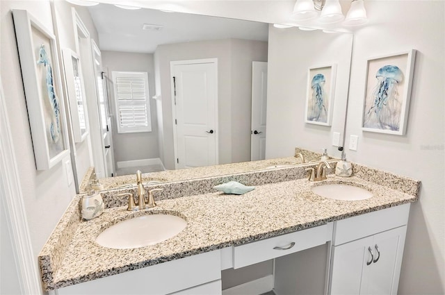 bathroom featuring a sink, baseboards, and double vanity