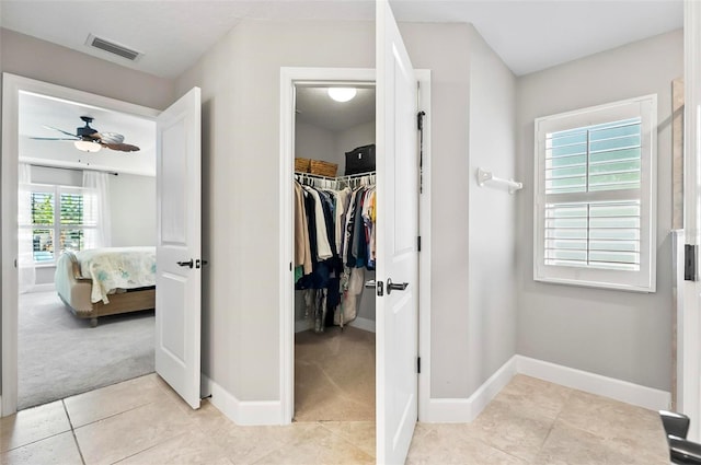 interior space featuring tile patterned floors, visible vents, a ceiling fan, connected bathroom, and baseboards