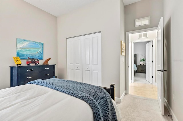 bedroom with visible vents, a closet, baseboards, light colored carpet, and a towering ceiling