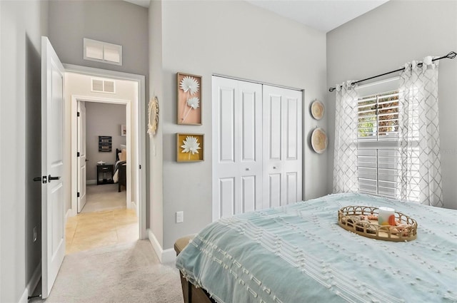 bedroom with baseboards, visible vents, light carpet, and a closet