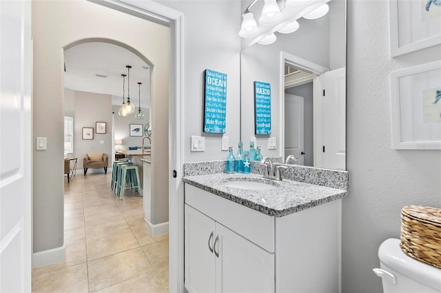 half bathroom featuring tile patterned flooring, toilet, vanity, and baseboards