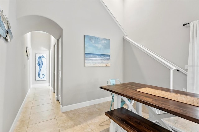 dining room featuring light tile patterned floors, baseboards, and arched walkways