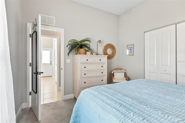 bedroom featuring light tile patterned floors, visible vents, baseboards, a closet, and light colored carpet