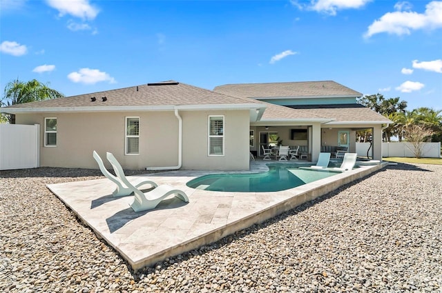 rear view of house with stucco siding, a patio, a fenced backyard, roof with shingles, and a fenced in pool