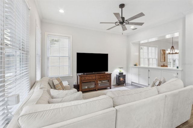 living room featuring crown molding, a wood stove, visible vents, and a wealth of natural light