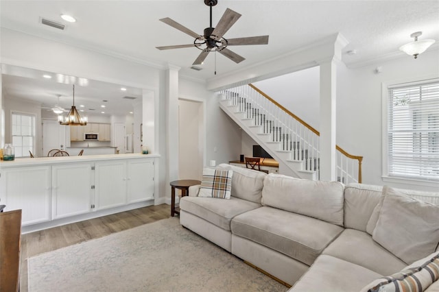 living room with visible vents, ceiling fan, stairs, crown molding, and light wood-type flooring