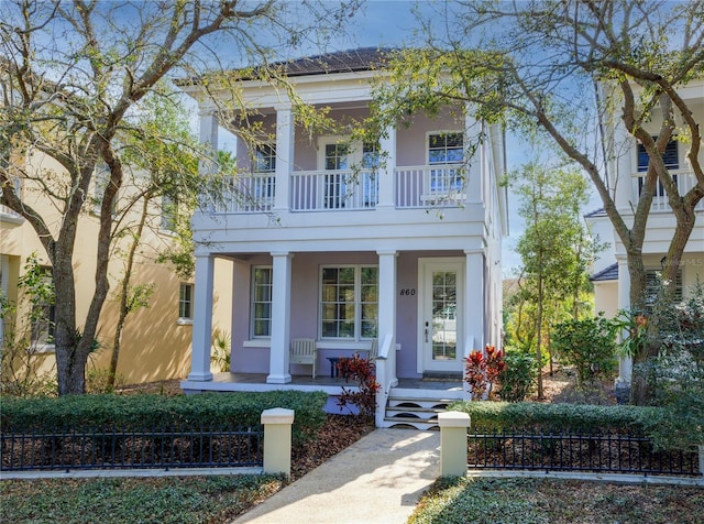 neoclassical home featuring covered porch and stucco siding