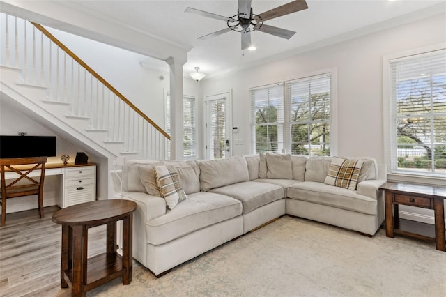 living room featuring light wood-style flooring, a ceiling fan, crown molding, and a healthy amount of sunlight