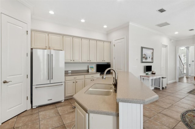 kitchen with visible vents, crown molding, freestanding refrigerator, light tile patterned flooring, and a sink