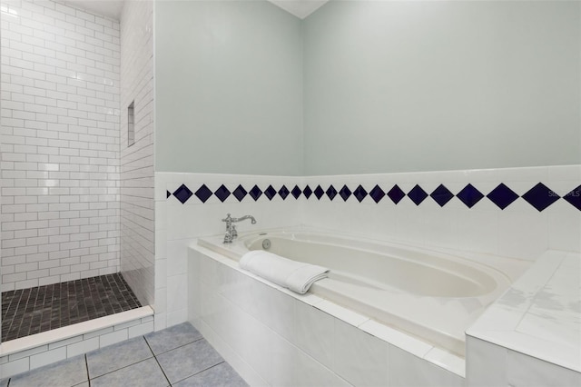 full bathroom featuring tile patterned flooring, a bath, and a tile shower