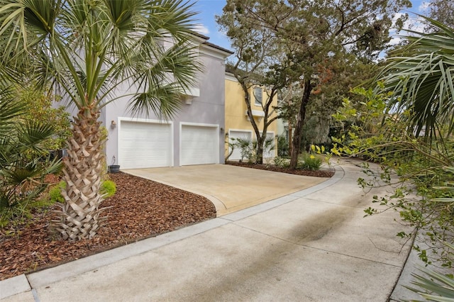 view of side of property with stucco siding, concrete driveway, and an attached garage