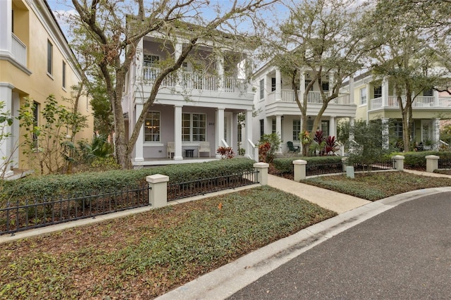 greek revival house featuring stucco siding, a balcony, and a porch