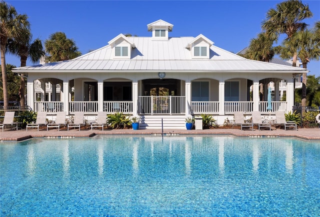 rear view of house featuring a patio area, metal roof, a standing seam roof, and a community pool