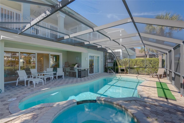 view of pool featuring a patio area, glass enclosure, and a pool with connected hot tub