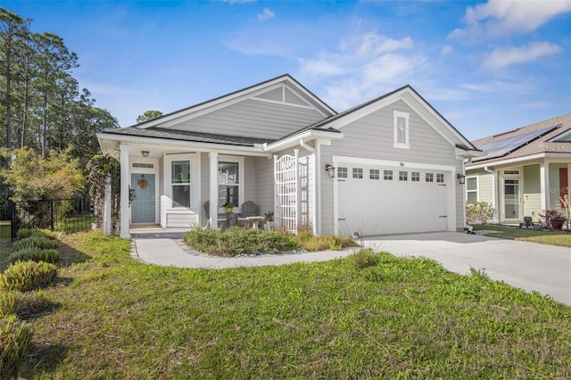 view of front of home featuring driveway, covered porch, an attached garage, and a front yard