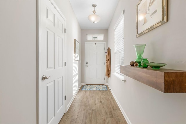 doorway featuring light wood-style flooring and baseboards