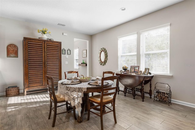 dining room featuring light wood-style flooring, visible vents, and baseboards