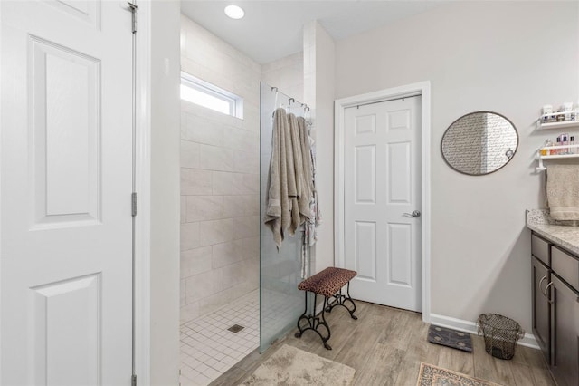 full bath with a walk in shower, wood finished floors, vanity, and baseboards