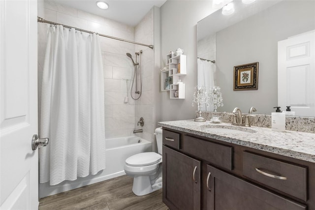 bathroom featuring toilet, shower / bath combo with shower curtain, wood finished floors, and vanity