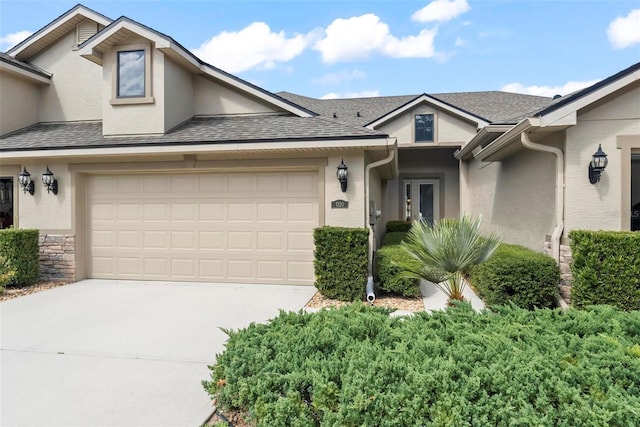 view of front of property featuring driveway, roof with shingles, and stucco siding