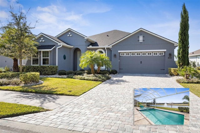 ranch-style home featuring a garage, a pool with connected hot tub, decorative driveway, stucco siding, and a front yard