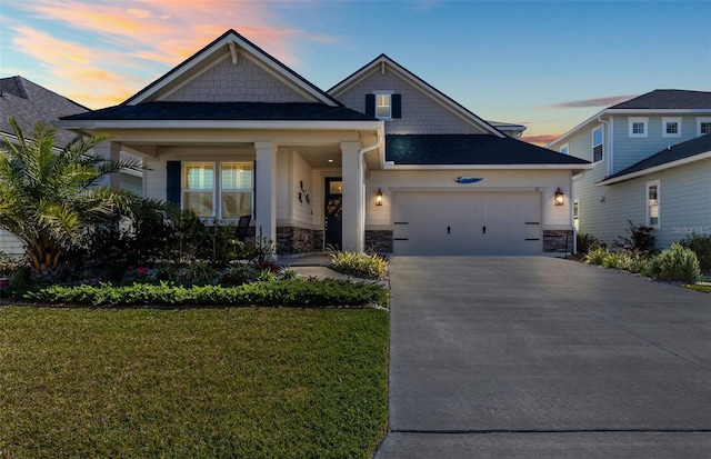 craftsman-style house with stone siding, a yard, a garage, and driveway