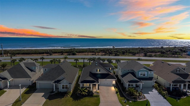 aerial view at dusk featuring a residential view and a water view