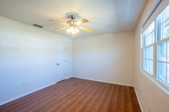 empty room featuring wood finished floors, baseboards, visible vents, ceiling fan, and a textured ceiling